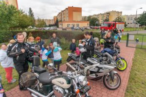 Grupa dzieci i dorosłych przy motocyklach